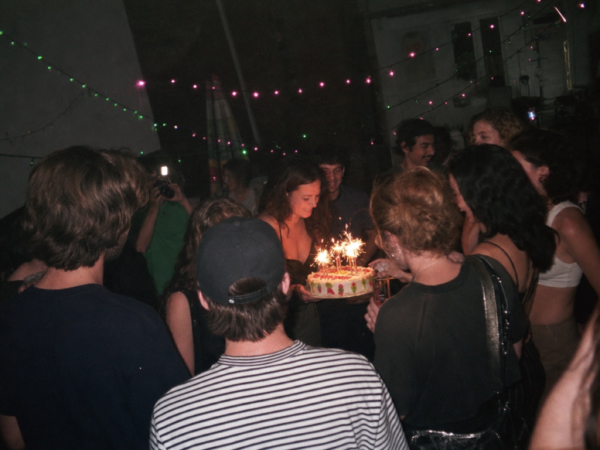 Amigos alrededor de un pastel de cumpleaños con luces de bengala, bajo series de luces